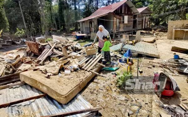 Atikah dan anak bongsunya mencari barangan masih boleh digunakan selepas sebahagian besar rosak ditenggelami banjir.