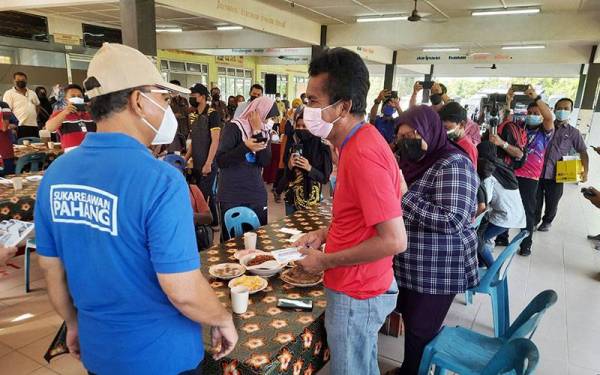 Wan Rosdy (kiri) beramah mesra dengan mangsa banjir selepas menyampaikan sumbangan di PPS Sekolah Menengah Kebangsaan Ubai, Pekan pada Selasa.