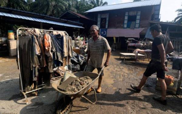 Penduduk kampung, Roslin Pahing, 52, melakukan kerja-kerja pembersihan selepas rumah pusakanya dilanda banjir ketika tinjauan di Kampung Labohan Dagang Kuala Langat, Banting.- Foto Bernama