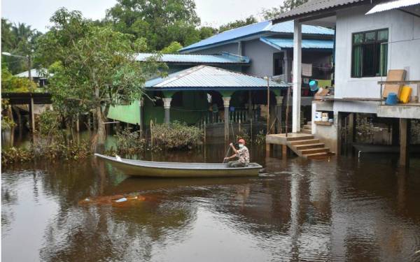 Penduduk mendayung sampan untuk keluar melakukan aktiviti harian berikutan kawasan kediaman masih digenangi air sejak seminggu lalu. - Foto Bernama
