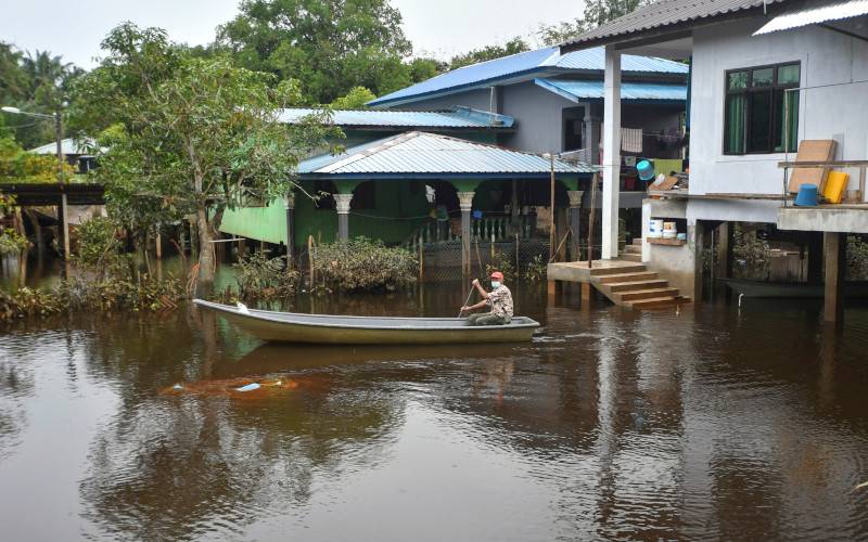 Penduduk mendayung sampan untuk keluar melakukan aktiviti harian berikutan kawasan kediaman masih digenangi air sejak seminggu lalu ketika tinjauan di Kampung Tersang, Rantau Panjang pada Rabu. - Foto Bernama