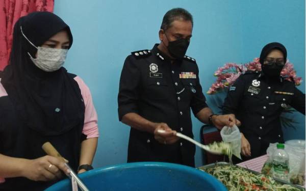 Asisten Komisioner S Vijaya Rao (tengah) membantu membungkus makanan untuk diagihkan kepada pegawai dan anggota yang terlibat banjir.