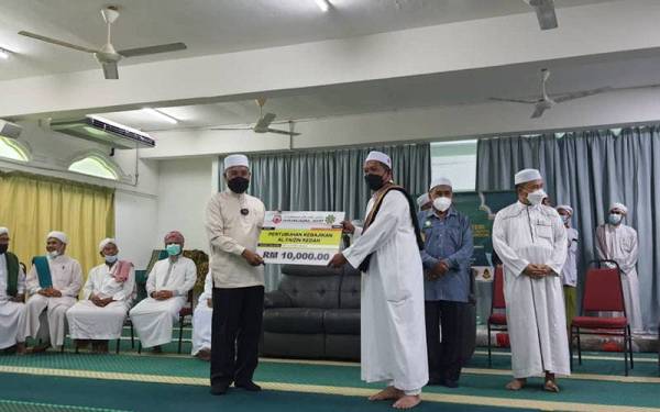 Idris (kiri) menyerahkan sumbangan kepada sebuah NGO Kedah selepas Program Dialog Bersama Tuan Guru Pondok Negeri Kedah di Madrasah Ar Rahmaniah Pondok Tuan Guru Haji Salleh pada Khamis.