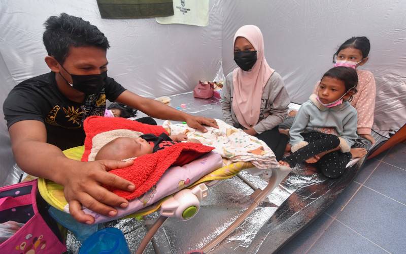 Mangsa banjir Mohd Jakari Suaman, 30, (kiri) bersama keluarga terpaksa berpindah ke PPS Dewan Kesedar Sungai Satan berikutan kawasan kediaman dinaiki air selepas hujan lebat sejak pagi semalam. Foto Bernama