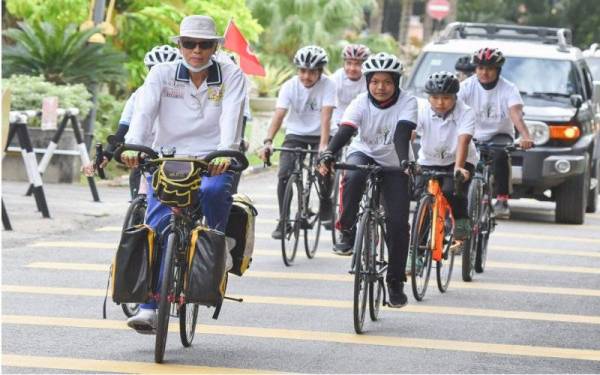 Wan Hashim (kiri) menamatkan kayuhan solo jelajah mengelilingi Semenanjung Malaysia buat kali ketujuh sejurus tiba di pekarangan Bangunan Mabna-MBI Kompleks Kota Darulnaim, pada Jumaat. - Foto Bernama 