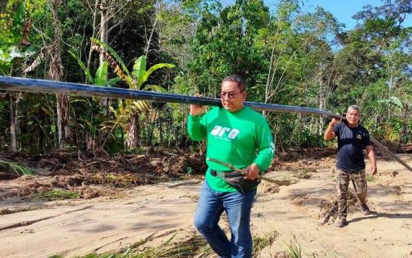 Muhammad Sanusi tidak kekok membantu mengangkat paip sepanjang dua meter di kampung orang asli di Paya Lebar, Hulu Langat. - Foto Facebook Dewan Pemuda Pas Negeri Kedah