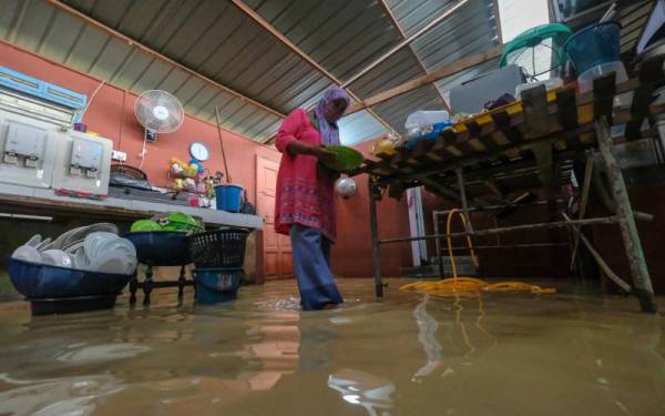 Penduduk setempat Nosimah Naim, 56, mula membersih barangan rumah yang terselamat dari banjir walaupun air masih bertakung di ruang dapur rumahnya ketika tinjauan banjir di Kampung Belimbing Dalam dekat Durian Tunggal hari ini. Foto Bernama