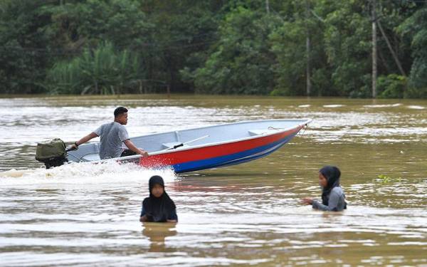 Penduduk menggunakan bot untuk pulang ke rumah selepas jalan terputus akibat banjir- Foto Bernama