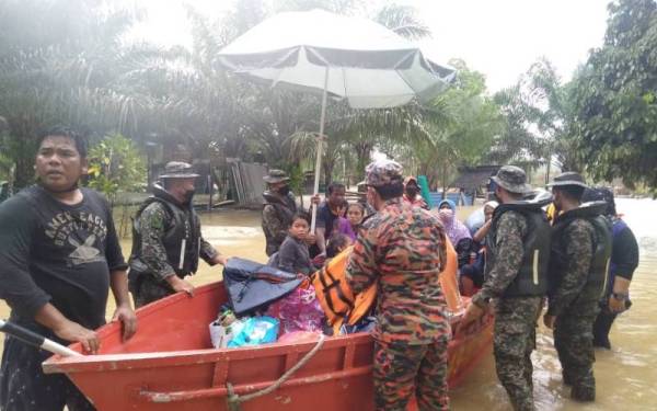 Anggota bomba, tentera dan APM membantu memindahkan 45 mangsa banjir yang terperangkap di Kampung Jemari, Mersing, sebelum membawa mereka ke PPS Politeknik Mersing, pada Isnin.