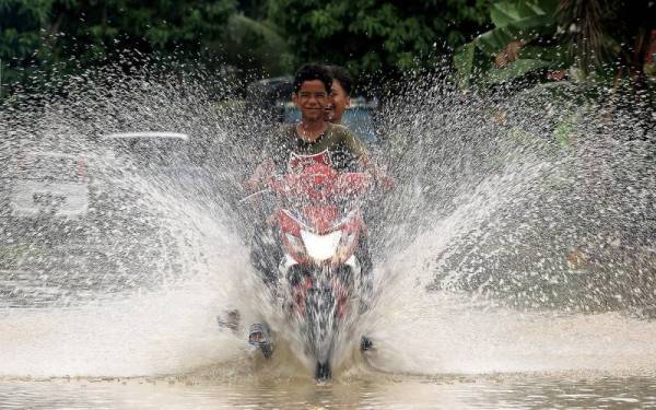  Penunggang motosikal meredah air banjir yang semakin surut di kawasan perumahan Taman Pinggiran Sungai Kelamah akibat ditenggelami banjir yang melanda baru-baru hari ini. - Foto Bernama