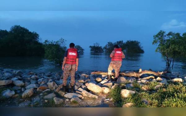 Dua anggota bomba memantau fenomena air pasang besar di pantai daerah ini pada Selasa.