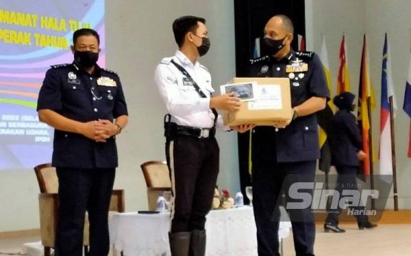 Mior Faridalathrash (kanan) menyampaikan sumbangan banjir kepada anggota yang terjejas pada Perhimpunan Bulanan Ketua Polis Perak dan Amanat Tahun Baharu 2022 di Dewan Serbaguna Pengkalan Latihan Pasukan Gerakan Udara (PLGPU) pada Selasa.