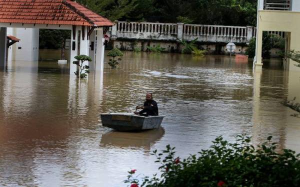 Kakitangan Galeri Darurat Bukit Kepong mengayuh sampan untuk meninjau keadaan sekitar Galeri Darurat Bukit Kepong yang dinaiki air berikutan limpahan Sungai Muar hari ini. - Foto Bernama