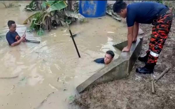 Anggota bomba terpaksa menyelam untuk memecahkan tangki yang menjadi punca sebuah parit di Kampung Segaliud, Kinabatangan tersumbat selepas banjir pada Isnin.