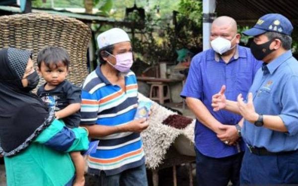 Ikmal Hisham (kanan) ketika menyampaikan sumbangan kepada Mat Sidek (dua dari kiri) sempena program Cakna Veteran ATM di Taman Seri Nanding, Hulu Langat baru-baru ini. - Foto Bernama