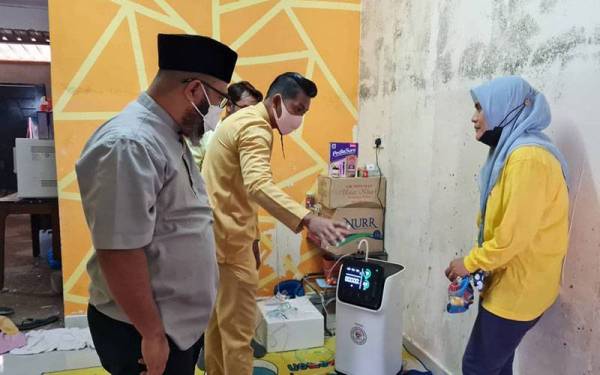 Dr Asmadi (kiri) menyerahkan alat bantuan pernafasan kepada Norfardilatul Akmar (kanan) di rumahnya pada petang Jumaat.