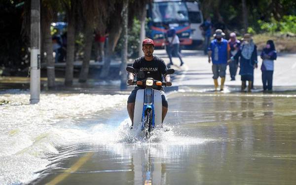 Air banjir di Kampung Spang Loi semakin surut membolehkan kenderaan ringan melepasi laluan yang dinaiki air untuk pulang ke kediaman masing-masing. - Foto Bernama 