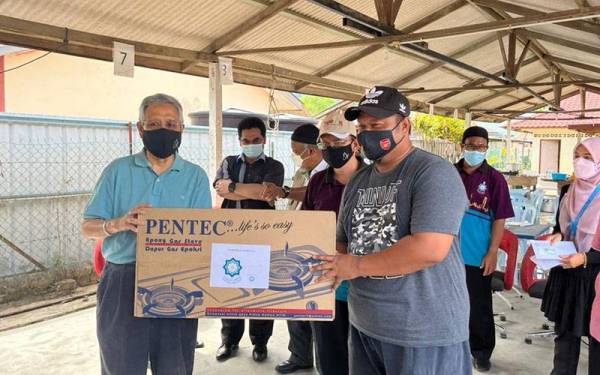 Abdul Aziz (kiri) menyampaikan barangan perkakasan rumah kepada mangsa banjir di Kampung Sungai Lui pada Sabtu.