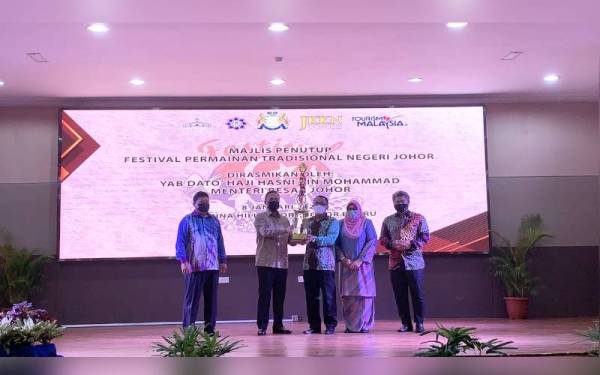 Mazlan (kiri) bersama Hasni (dua,kiri) ketika menyampaikan piala kepada juara keseluruhan Festival Permainan Tradisional di sini pada Sabtu.