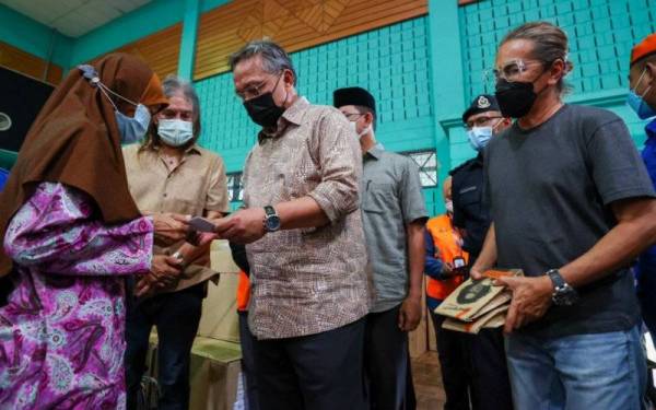 Hasni (depan, dua dari kanan) bersama Amy Search (depan, kanan) beramah mesra dan menyampaikan bantuan kepada mangsa banjir semasa lawatan ke PPS Pagoh, Muar pada Sabtu. - Foto Pejabat Menteri Besar Johor