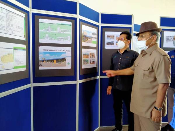 Mohd Fasiah (kiri) dan Tajuddin melihat pelan pembangunan PTK Kampung Gajah dalam lawatan kerja ke kompleks tersebut di sini pada Ahad.