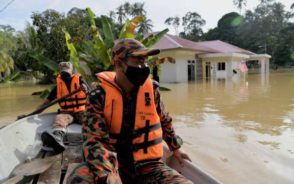 Ketua Balai Bomba dan Penyelamat (BBP) Bukit Gambir Penolong Penguasa Bomba Mohd Farizan Mokhtar (depan) melakukan pemantauan di kawasan yang terjejas banjir di Kampung Kurnia Sakti hari ini. - Foto Bernama