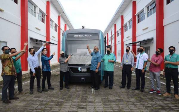 Abdul Aziz (lima dari kiri) serta kumpulan penyelidik UMP menunjukkan bas pintar SCAV yang dibangunkan.