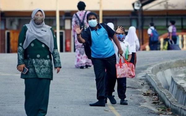 Gelagat dua orang murid Sekolah Kebangsaan Pantai melambai tangan ke arah ayahnya yang menunggu di luar pagar sekolah sebelum memasuki perkarangan sekolah bagi memulakan sesi pembelajaran di sekolah tersebut pada Isnin. - Foto Bernama