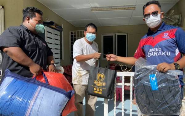 Mohd Nizam (kanan) menyampaikan bantuan kit ibadah kepada mangsa banjir.