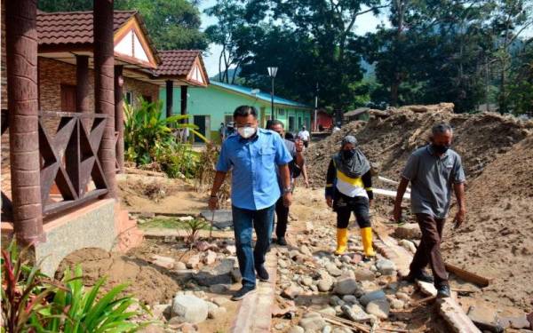 Mohd Sharkar (kiri) meninjau kesan kemusnahan akibat banjir besar yang berlaku Disember lepas di kawasan Rekreasi Pulau Santap Janda Baik pada Isnin. - Foto Bernama 