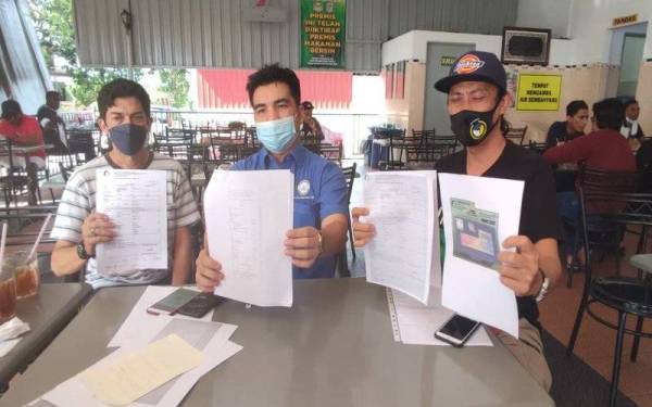 Setiausaha Cake, Mohamad Yusrizal Yusoff (tengah) menunjukkan dokumen tempoh cukai jalan dan insurans yang tidak selaras ketika ditemui pemberita di sebuah restoran di Taman Tunku Haminah, di sini, pada Ahad.