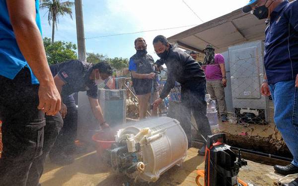 Ismail Abd Muttalib membantu membaik pulih peralatan elektrik pasca banjir dalam program SWCorp Bersamamu serta agensi kemahiran di Taman Sri Nanding, Hulu Langat hari ini. -Foto Bernama