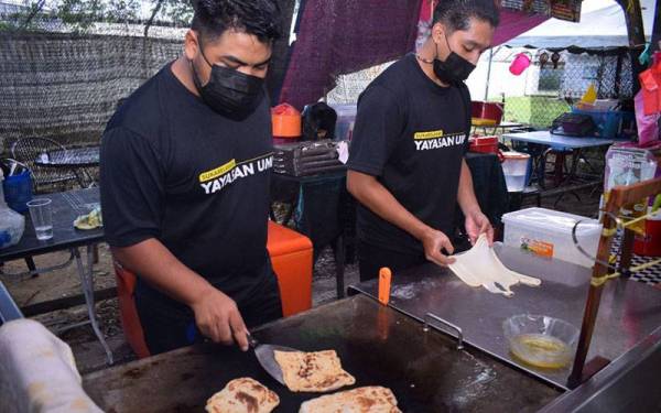 Muhammad Hisammudin (kanan) bersama rakannya, Muhammad Zubair Faiz Zulkefly menyediakan roti canai untuk diedarkan kepada mahasiswa UMP pada Sabtu.