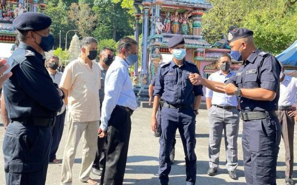 Mohd Shuhaily (dua dari kanan) dan Subramaniam (tiga dari kiri) mendengar penerangan daripada Ketua Polis Daerah Timur Laut, Asisten Komisioner Soffian Santong ketika melawat Kuil Hilltop, Georgetown pada Rabu.