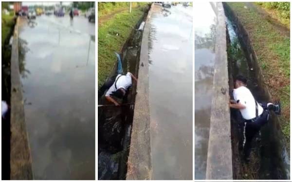 Koperal Shah Erman yang lengkap berpakaian seragam masuk ke dalam longkang untuk membersihkan lubang yang tersumbat di Kampung Meruntum, Putatan.