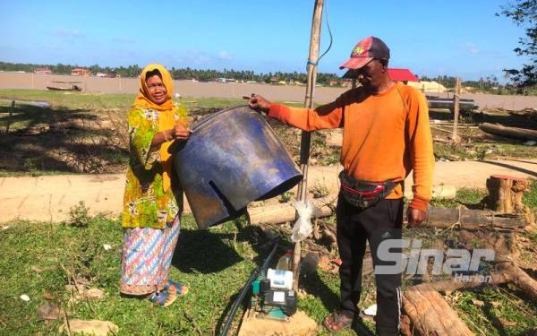 Siti Rabiah dan Mahadi menunjukkan pam yang digunakan untuk menyalurkan air dari sungai ke rumah penduduk