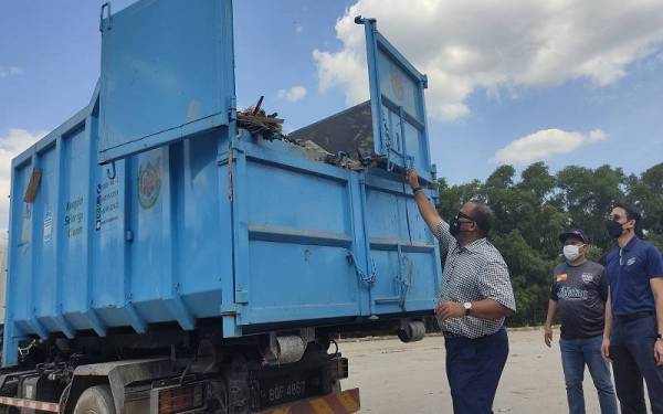 Ramli (tiga dari kanan) menutup pintu tong RORO terakhir di Stesen Pemindahan Sisa Pepejal Seksyen 21, di sini pada Jumaat.