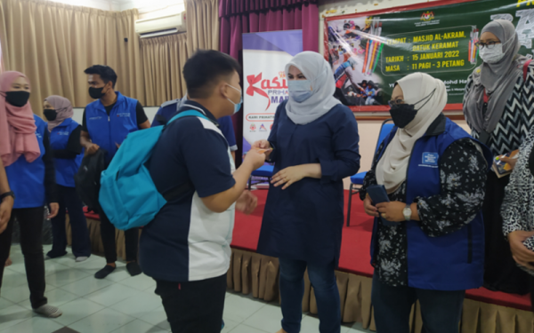 Rina menyampaikan bantuan persekolahan kepada salah seorang penerima bantuan Program Back to School Parlimen Titiwangsa, di Masjid Al-Akram Datuk Keramat di sini pada Sabtu.