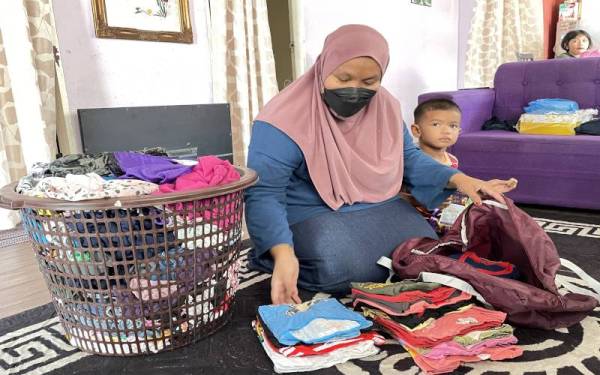 Siti Samsiah sedang mengemas pakaian sebagai persiapan berpindah sementara ke rumah saudaranya.