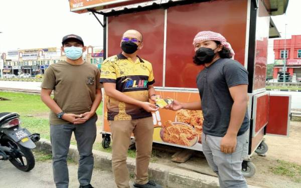 Mohamad Rozlan (tengah) menyampaikan sumbangan kepada Zaquan Jamaluddin, 30, yang melecur tersimbah minyak panas ketika kejadian ribut yang berlaku di Bandar Meru Raya.