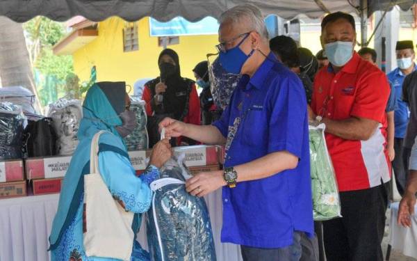 Perdana Menteri Datuk Seri Ismail Sabri Yaakob (tengah) menyampaikan bantuan kepada penduduk Kampung Guai, Azizah Awg Lazi (kiri) pada Program Santunan Mangsa Banjir anjuran Jabatan Kemajuan Masyarakat (Kemas) di Kampung Guai hari ini. - Foto Bernama