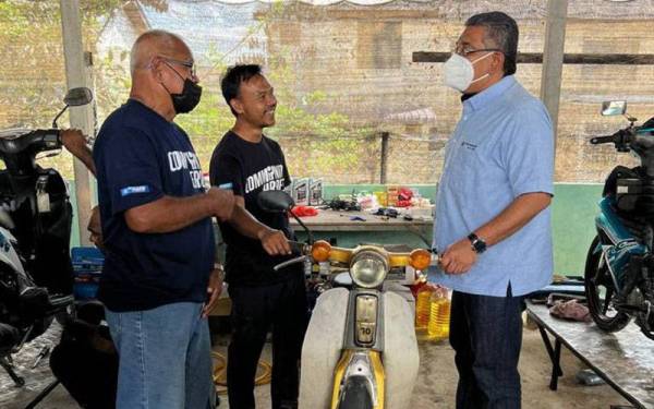 Megat Zulkarnain (kanan) turun padang meninjau perjalanan program membaiki motosikal mangsa banjir di Mentakab, Temerloh pada Sabtu.