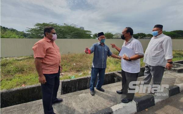 Muhamad Farid (dua, kanan) bersama pemimpin masyarakat kawasan Teluk Kumbar meninjau salah satu lokasi cadangan pembinaan asrama pekerja asing yang sudah dipagar.