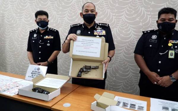 Mior Faridalathrash (tengah) menunjukkan sepucuk pistol jenis Revolver.38 yang dirampas daripada pasangan suami isteri dalam serbuan Op Tapis Khas Kontinjen Perak.