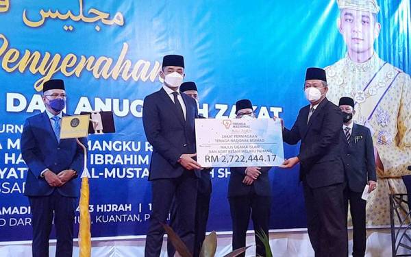 Hassan (depan kanan) menyerahkan replika bayaran zakat TNB kepada Tengku Hassanal (depan kiri) pada majlis penyerahan zakat perniagaan di Hotel Grand DarulMakmur, Kuantan pada Selasa.