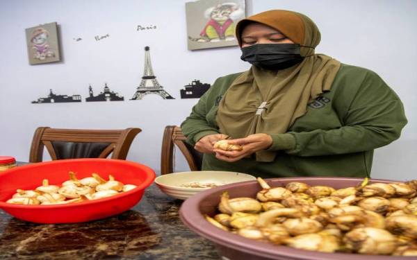 Rohayu mengupas ubi ngaku sebelum diparut serta digoreng untuk dijual kepada pelanggan secara dalam talian dan kaedah bayar selepas terima (COD) ketika ditemui Bernama di kediamannya di Kampung Panji, baru-baru ini. Foto Bernama
