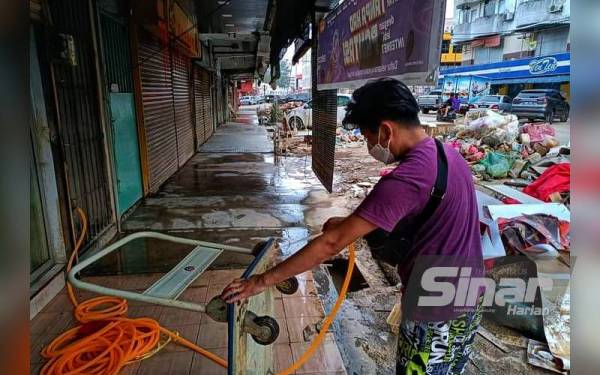 Chin Kok ketika membersihkan premis selepas banjir surut di bandar Mentakab baru-baru ini.