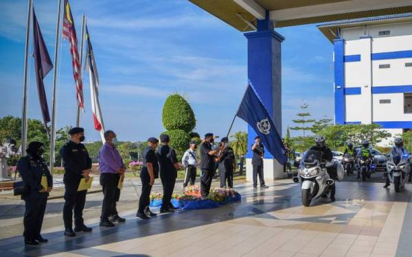 Abdul Majid mengibarkan bendera sebagai gimik pelancaran Op Tahun Baharu Cina pada majlis pelancaran tersebut di Ibu Pejabat Kontinjen Melaka, Bukit Beruang pada Khamis. - Foto Bernama