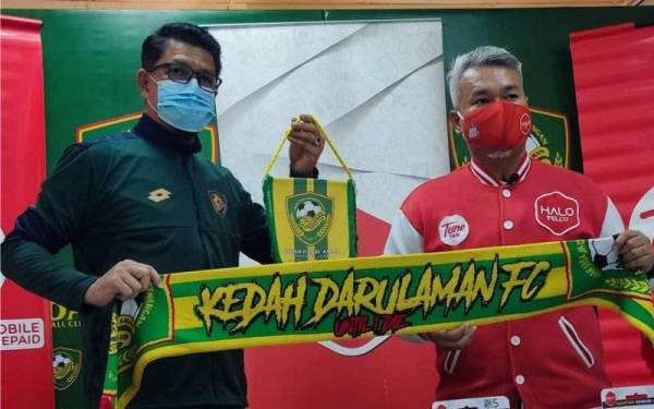 Khamal Idris (kiri) menyerahkan cenderamata kepada Mohd Shukrie selepas Majlis Tandatangan Perjanjian Rakan Rasmi KDA FC dan Pelancaran Produk Eksklusif KDA FC & Halo Telco di Alor Setar pada Khamis.