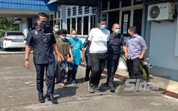 Tertuduh berbaju t-shirt putih, coklat dan biru diiringi anggota polis sebaik selesai pertuduhan.